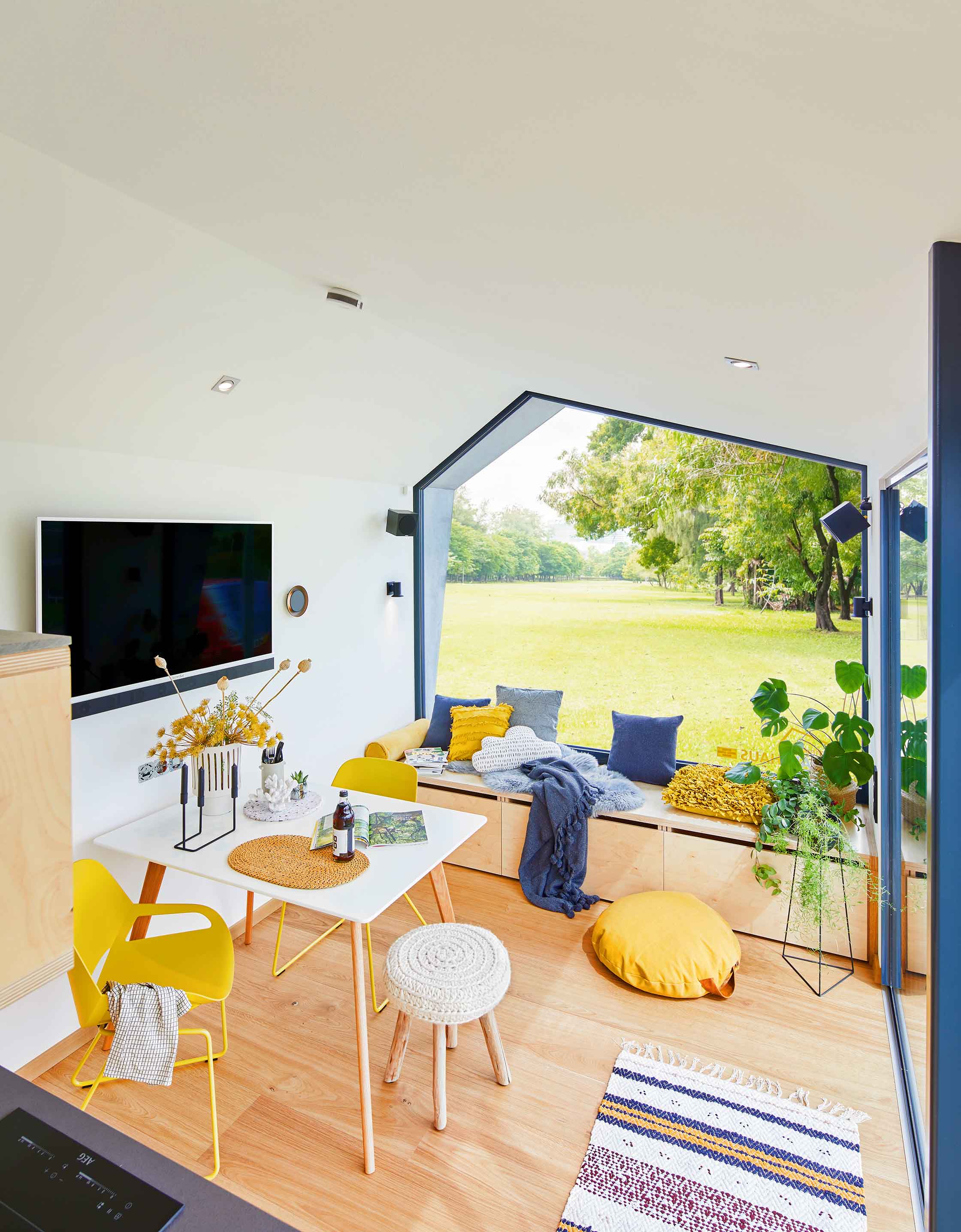 Tiny Houses Wohnen und Leben auf wenig Raum. Tiny Smart Haus Innenansicht mit Blick nach draußen durch das Panoramafenster.